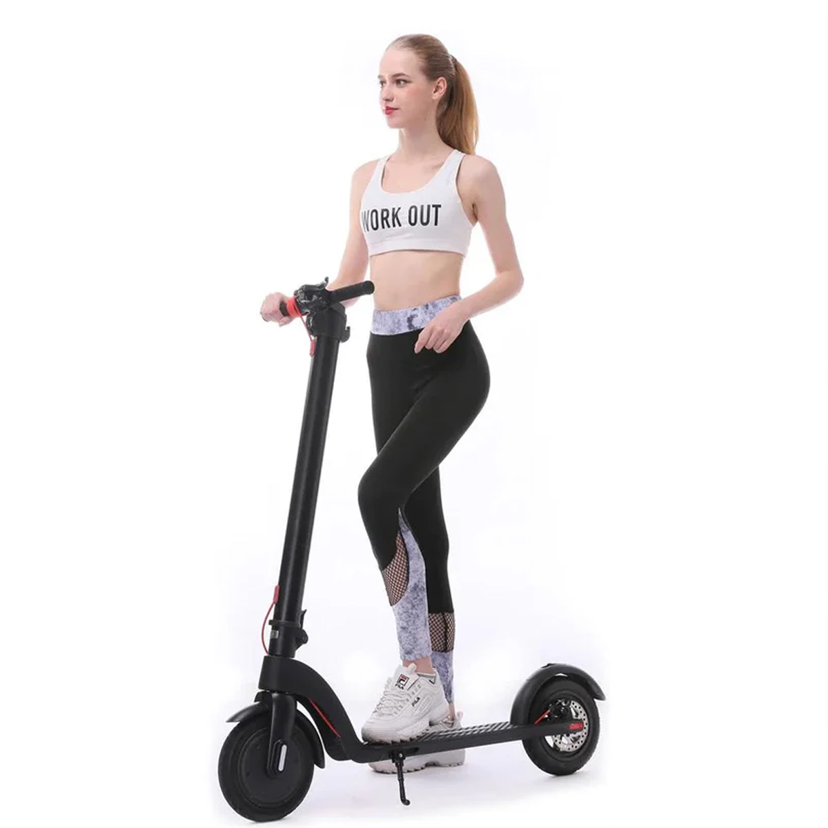 A woman in workout clothes stands next to an X7 500w Foldable E-Scooter With Replaceable/Detachable Lithium Battery, 8.5-inch pneumatic tires (Black), wearing a white WORK OUT sports bra, black mesh-detailed leggings, and white sneakers.